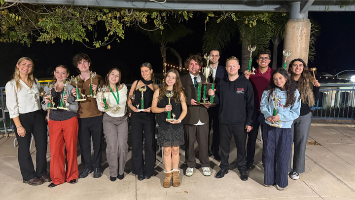 SDSU Forensics Team members pose with trophies and medals after a tournament.