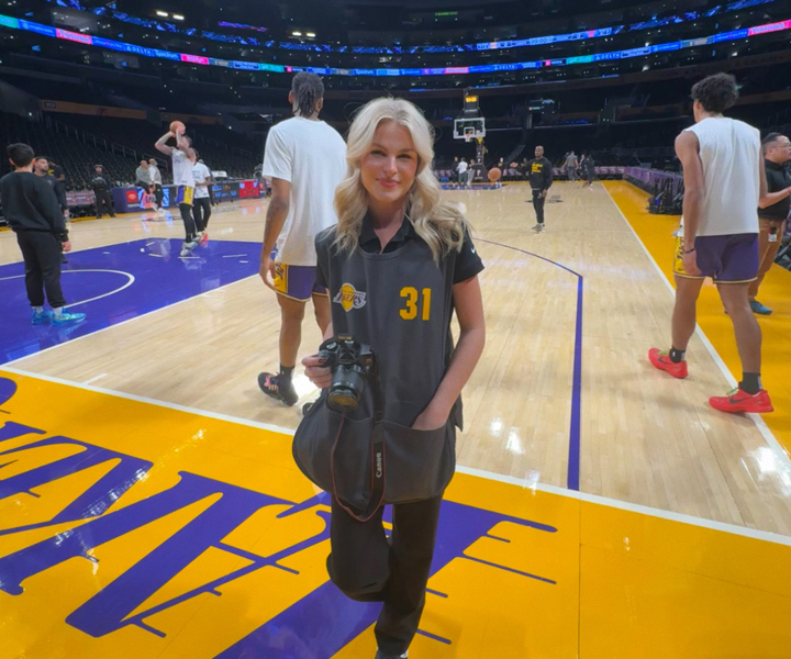 intern standing on basketball court holding camera