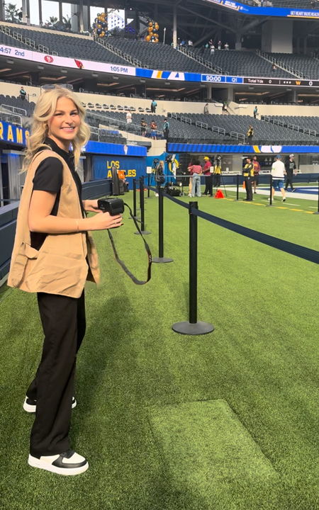 intern standing on field holding camera